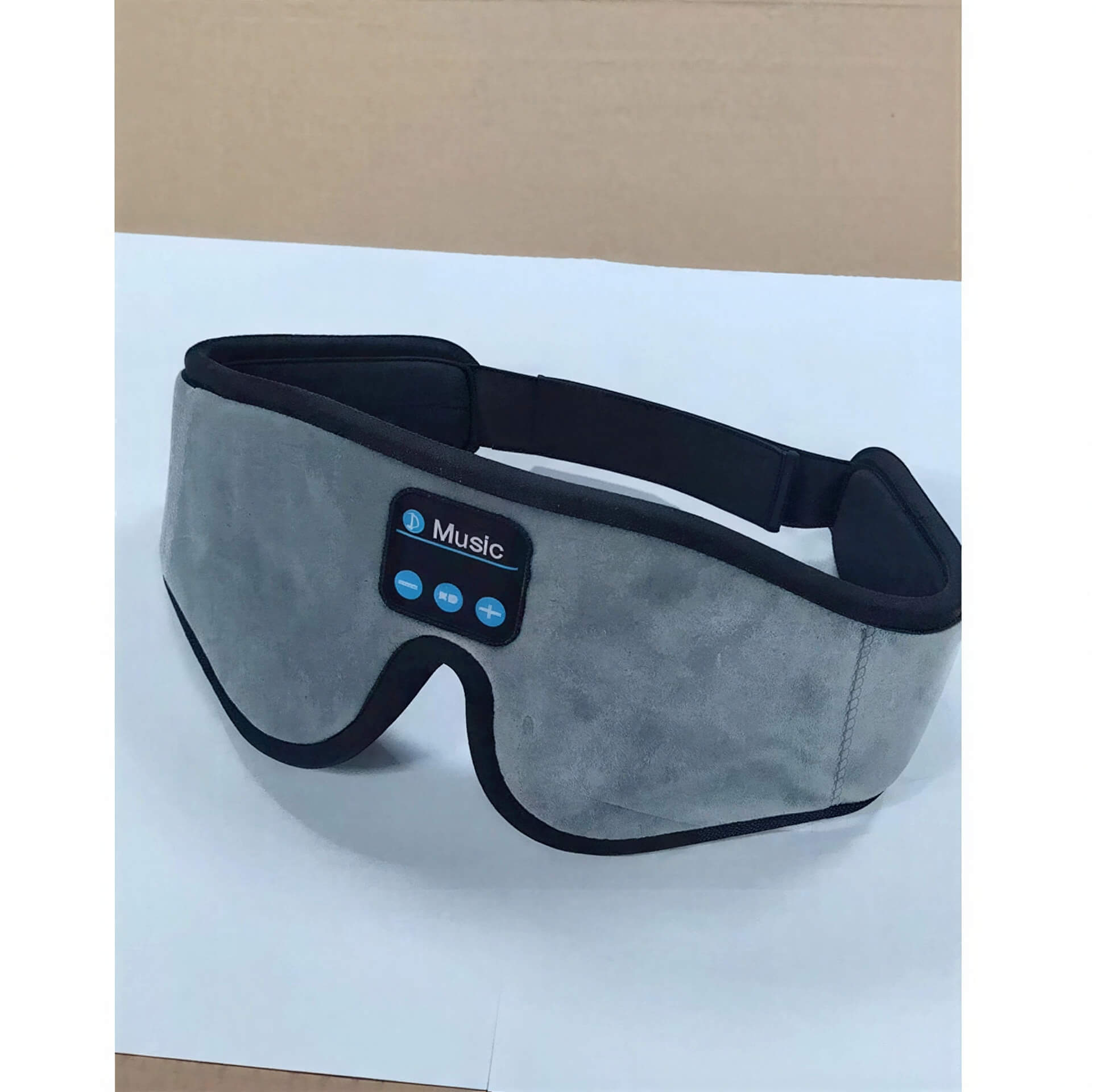 Gray 3D eye mask with Bluetooth controls for music, featuring a soft fabric exterior and adjustable strap.
